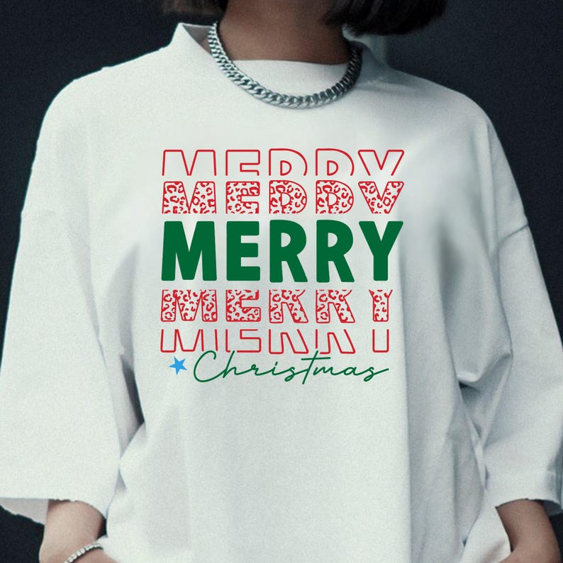 Puede incluir: Sudadera blanca de cuello redondo con las palabras "MERRY CHRISTMAS" en rojo, verde y estampado de leopardo. La palabra "MERRY" est&aacute; en letras verdes grandes. Una estrella est&aacute; al lado de la palabra "Christmas".
