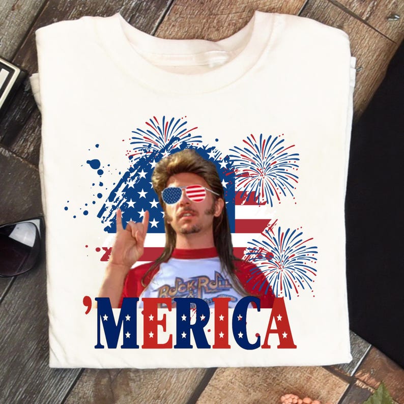 Op de afbeelding: Wit t-shirt met een afbeelding van een man met een zonnebril in de kleuren van de Amerikaanse vlag, een rood-wit shirt en een mullet. Het woord "'MERICA" staat in rode en blauwe letters, met vuurwerk en de Amerikaanse vlag op de achtergrond.