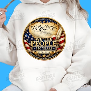 K&ouml;nnte beinhalten: Ein wei&szlig;er Kapuzenpullover mit einem kreisf&ouml;rmigen Aufdruck mit dem Text We The People, 250 Years, 1776-2026, Celebrating Liberty sowie Honoring Our Past, Inspiring Our Future. Das Design zeigt eine Pergamentrolle, eine Feder und eine US-Flagge.