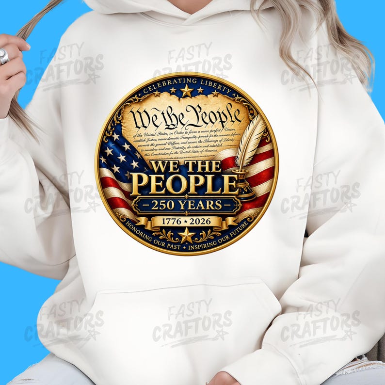 K&ouml;nnte beinhalten: Ein wei&szlig;er Kapuzenpullover mit einem kreisf&ouml;rmigen Aufdruck mit dem Text We The People, 250 Years, 1776-2026, Celebrating Liberty sowie Honoring Our Past, Inspiring Our Future. Das Design zeigt eine Pergamentrolle, eine Feder und eine US-Flagge.