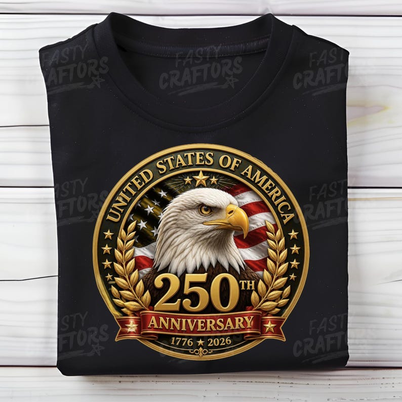 K&ouml;nnte beinhalten: Ein schwarzes T-Shirt mit einem kreisf&ouml;rmigen Motiv, das einen Wei&szlig;kopfseeadler, die amerikanische Flagge und goldene Lorbeerbl&auml;tter zeigt. Der Text lautet UNITED STATES OF AMERICA, 250TH ANNIVERSARY und 1776-2026, mittig auf der Brust.