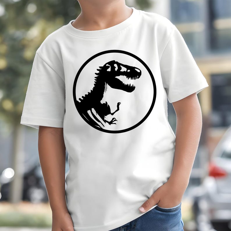 May include: White t-shirt featuring a black dinosaur silhouette inside a black circle. The dinosaur is a Tyrannosaurus Rex, with its head turned to the right and its mouth open. The shirt is short-sleeved and appears to be made of cotton.