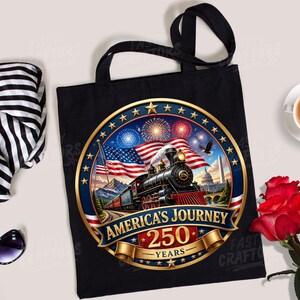 K&ouml;nnte beinhalten: Eine schwarze Tragetasche mit einem kreisf&ouml;rmigen Motiv, das eine Dampflokomotive, eine amerikanische Flagge, Feuerwerk und den Text America's Journey 250 Years zeigt. Das Design umfasst einen goldenen Rand mit Sternen und ein Regierungsgeb&auml;ude.