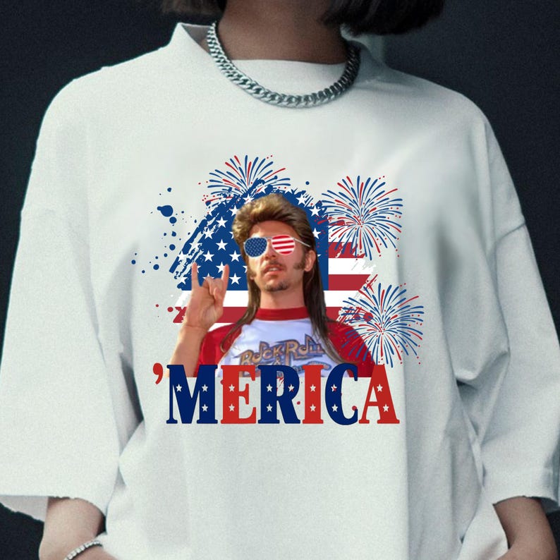 Op de afbeelding: Wit T-shirt met een afbeelding van een man met een zonnebril in de stijl van de Amerikaanse vlag, een hanenkam en het woord "'MERICA" in rood, wit en blauw. Het ontwerp bevat vuurwerk en een Amerikaanse vlag achtergrond.