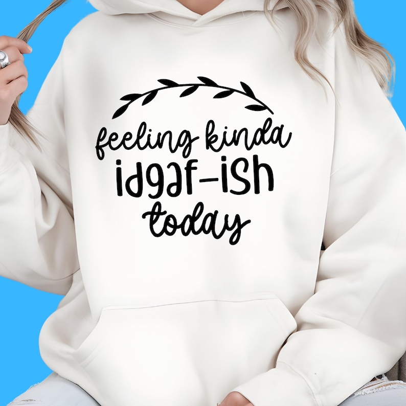 K&ouml;nnte beinhalten: Cremefarbener Kapuzenpullover mit schwarzem Aufdruck "feeling kinda id9af-ish today" und einem schwarzen Blattdesign. Der Hoodie hat eine Vordertasche und eine Kapuze.