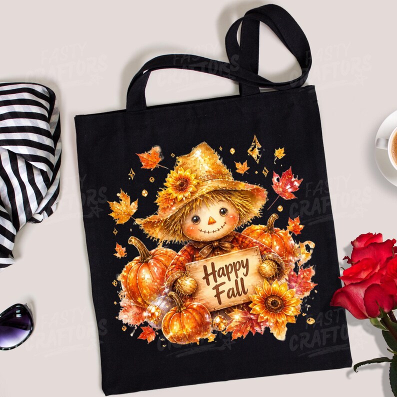 May include: A black tote bag featuring a graphic of a scarecrow wearing a straw hat, surrounded by orange pumpkins, yellow sunflowers, and autumn leaves. The scarecrow holds a wooden sign with the text Happy Fall printed in brown letters.
