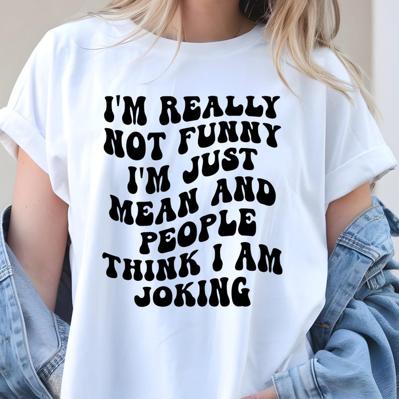 K&ouml;nnte beinhalten: Wei&szlig;es T-Shirt mit dem schwarzen Text: "I'M REALLY NOT FUNNY I'M JUST MEAN AND PEOPLE THINK I AM JOKING." Das Shirt hat kurze &Auml;rmel und eine lockere Passform. Der Text ist fett und abgerundet.