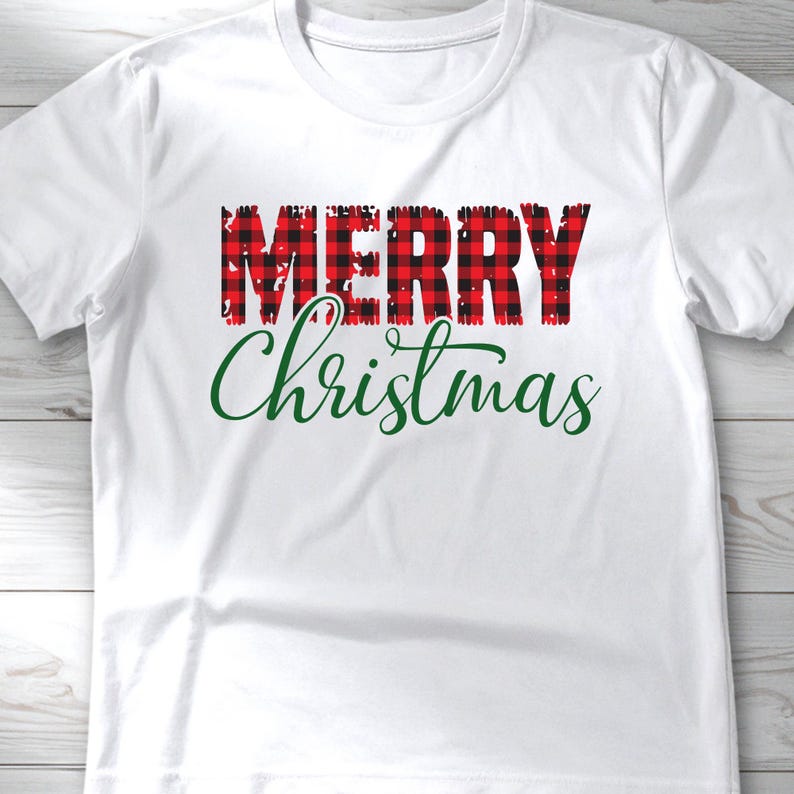 Puede incluir: Camiseta blanca con las palabras "MERRY" en letras a cuadros rojas y negras sobre la palabra "Christmas" en escritura verde. Una prenda casual y festiva.