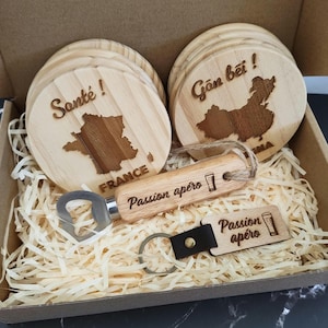 Peut inclure: Un coffret cadeau avec des dessous de verre en bois, un ouvre-bouteille et un porte-clés. Les dessous de verre présentent des contours de pays et les mots "Santé!" et "Gān bēi!". L'ouvre-bouteille et le porte-clés sont gravés "Passion apéro".