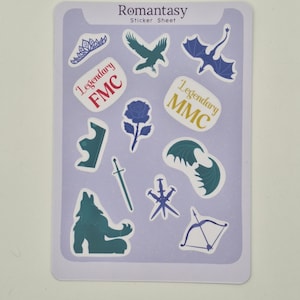 Puede incluir: Una hoja de pegatinas con la palabra "Romantasy" en la parte superior. La hoja presenta varias pegatinas, incluyendo una corona, un cuervo, un dragón, una rosa, una espada y los textos "Legendary FMC" y "Legendary MMC". Las pegatinas son en tonos azules y blancos.