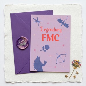 May include: A purple envelope with a wax seal next to a lavender card with the text "Legendary FMC" and illustrations of a dragon, wolf, bow and arrow, and rose. The card and envelope are on a textured white surface.