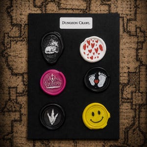 Könnte beinhalten: Eine schwarze rechteckige Karte mit der Aufschrift "DUNGEON CRAWL" und sechs Wachssiegeln. Die Siegel zeigen einen schwarzen Wolf, einen weißen Kreis mit roten Herzen, eine rosa Krone, einen schwarzen Kreis mit weißen Babyfüßen und einem roten Herz, eine schwarze Raptorkralle und ein gelbes Smiley-Gesicht.