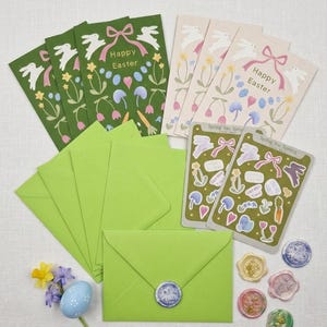 May include: An Easter-themed stationery set featuring green and cream-colored cards with bunny and floral designs. Includes green envelopes, stickers, and wax seals. The cards read "Happy Easter" and "Spring has Sprung".