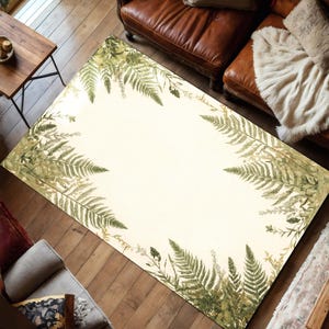May include: A rectangular rug featuring a cream central area framed by a border of green fern leaves. The rug is positioned on a wooden floor, creating a natural, botanical aesthetic. The image is taken from an overhead perspective.