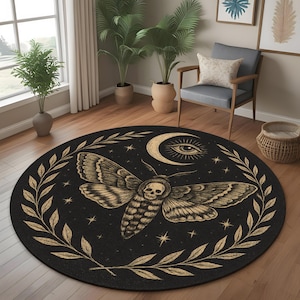 Op de afbeelding: Rond zwart tapijt met een gedetailleerd motontwerp, met een schedel, maan, sterren en een laurierkrans. De mot is in bruintinten, tegen een zwarte achtergrond. Een decoratief woonaccessoire.