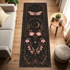 Könnte beinhalten: Schwarzer Läufer mit einem himmlischen Design mit einem rosa Schmetterling, einem Halbmond und floralen Elementen. Der Teppich hat einen detaillierten Rand und liegt auf einem Holzboden.