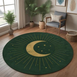Pode incluir: Um tapete redondo verde escuro com um design de lua crescente e estrelas douradas. Raios dourados emanam da lua, criando um padrão celestial. O tapete está colocado sobre um chão de madeira em uma sala com plantas e uma cadeira.