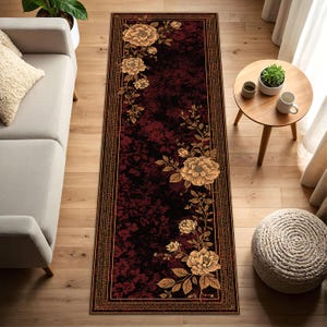 May include: A rectangular runner rug with a dark red and black floral pattern. The rug features a border and floral accents in shades of gold and brown. The rug is placed on a hardwood floor.
