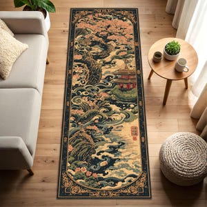 Könnte beinhalten: Ein rechteckiger Teppich mit japanisch inspiriertem Design. Der Teppich hat einen dunkelblauen Rand mit einem detaillierten Blumenmuster. Das zentrale Design zeigt eine Landschaft mit einer Pagode, Kirschblüten und fließendem Wasser in Blau-, Beige- und Rosatönen.