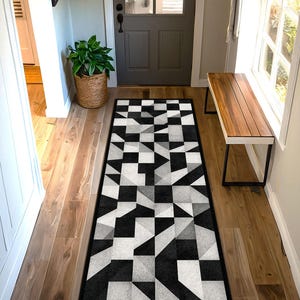 May include: Geometric patterned runner rug in black, white, and grey. The rug features a repeating design of squares and triangles, creating a modern, abstract look. The rug is rectangular and placed in a hallway.