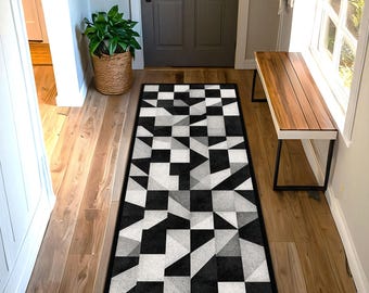 Puede incluir: Alfombra de pasillo con estampado geométrico en negro, blanco y gris. La alfombra presenta un diseño repetitivo de cuadrados y triángulos, creando un aspecto moderno y abstracto. La alfombra es rectangular y está colocada en un pasillo.
