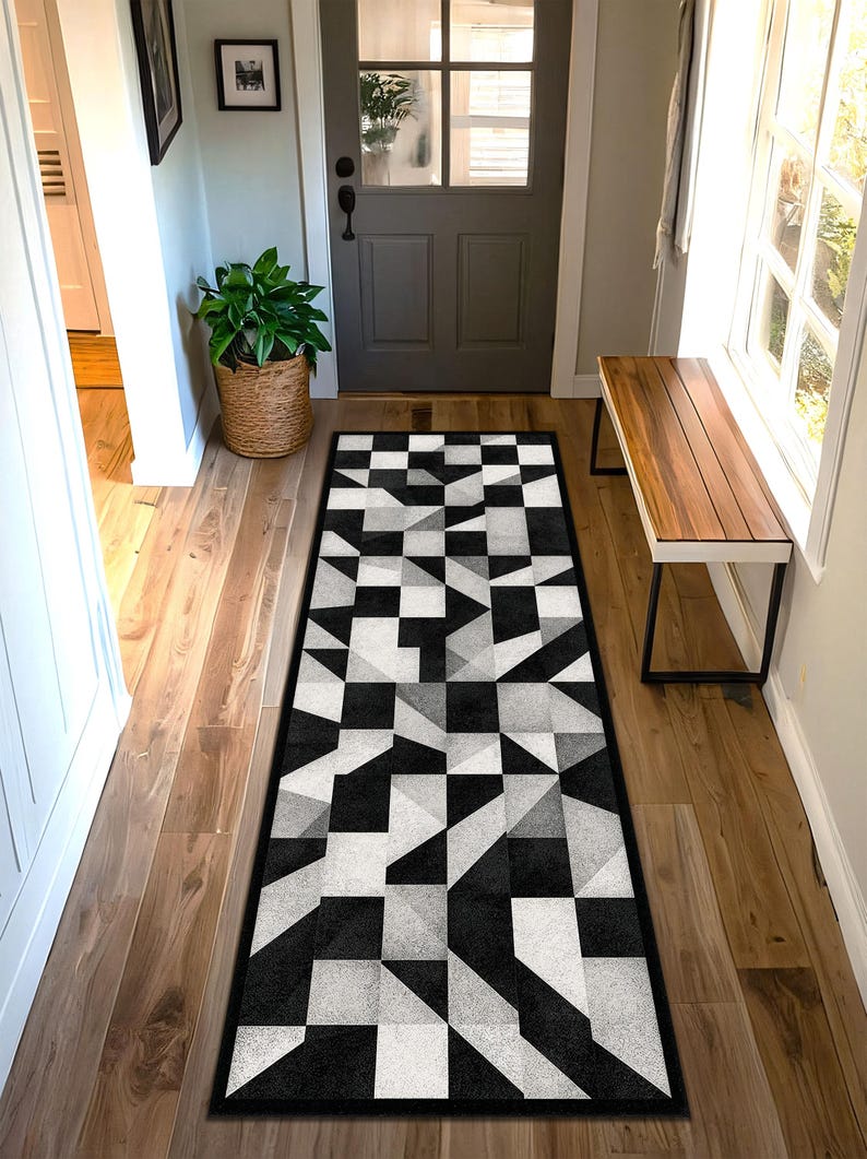 May include: Geometric patterned runner rug in black, white, and grey. The rug features a repeating design of squares and triangles, creating a modern, abstract look. The rug is rectangular and placed in a hallway.