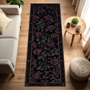 Può includere: Un lungo tappeto rettangolare con sfondo nero e un motivo floreale di rose nei toni del viola e del grigio. Il tappeto ha un bordo decorativo ed è posizionato su un pavimento in legno.