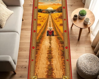 May include: A rectangular rug featuring a rural landscape with a red tractor on a dirt road leading to a sunset. The rug has a red border with heart and wheat stalk designs, creating a rustic, farmhouse aesthetic.