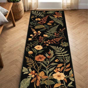 Pu&ograve; includere: Un lungo tappeto rettangolare con sfondo nero e motivo floreale. Il design presenta fiori e foglie arancioni, gialli e verdi. Il tappeto &egrave; posato su un pavimento in legno.