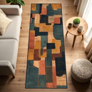 May include: A rectangular area rug with an abstract design. The rug features a pattern of geometric shapes in shades of teal, orange, mustard yellow, and brown. The rug is placed on a hardwood floor, and the overall aesthetic is modern and artistic.