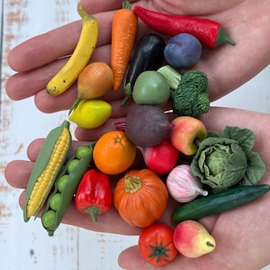 Pode incluir: Uma coleção de frutas e legumes em miniatura, incluindo uma banana amarela, cenoura laranja, pimenta vermelha, ameixa roxa, brócolis verde, espiga de milho, laranja, pimentão vermelho, abóbora, tomate, pera, alho, repolho e um pepino.