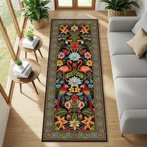 May include: A rectangular black rug with a floral and bird design. The rug features two pink flamingos, two parrots, and two toucans. The border is teal with a floral pattern. The rug is placed on a wooden floor.