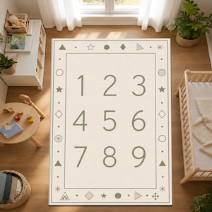 May include: A rectangular beige rug with numbers 1 through 9 in a green font. The rug has a border with geometric shapes and stars. The rug is on a wooden floor, and there is a small wooden table and a crib nearby.