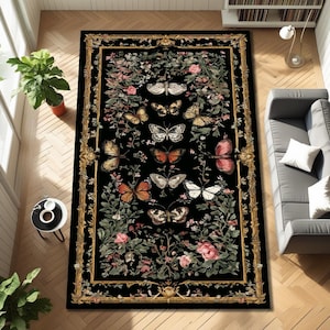 May include: A rectangular black rug with a gold border and a floral and butterfly design. The rug features various butterflies in shades of orange, white, and brown, surrounded by pink roses and green foliage. The rug is placed on a wooden floor.