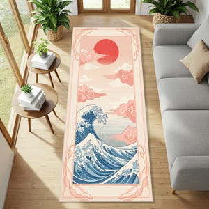 Könnte beinhalten: Rechteckiger Teppich mit japanisch inspiriertem Design. Der obere Teil zeigt eine rote Sonne und rosa Wolken, während der untere Teil eine große blaue und weiße Welle zeigt. Der Teppich ist mit einem hellrosa Rand eingefasst.
