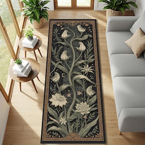 Puede incluir: Una alfombra rectangular negra con un diseño floral. La alfombra presenta un patrón central de flores blancas estilizadas y hojas verdes sobre un fondo oscuro. Un borde decorativo en color dorado enmarca el diseño. La alfombra está colocada sobre un suelo de madera.