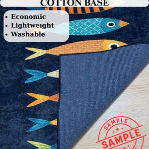 May include: A navy blue rug with a fish pattern in orange, blue, and yellow. The rug has a cotton base and is described as economic, lightweight, and washable. The word "SAMPLE" is stamped on the rug.