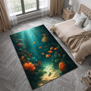 May include: A rectangular area rug featuring an underwater scene with orange fish, coral, and plants. The rug has a teal and blue background with light rays shining through the water. The rug is placed on a gray wooden floor.
