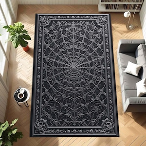 Può includere: Un tappeto rettangolare nero con un disegno a ragnatela. Il tappeto ha un bordo decorativo con dettagli floreali e a volute. Il motivo a ragnatela è centrato e copre la maggior parte della superficie del tappeto. Il tappeto è posto su un pavimento in legno.