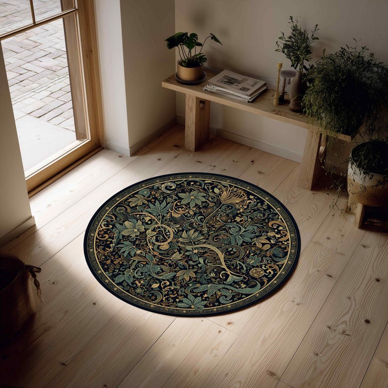 Op de afbeelding: Een ronde vloerkleed met een gedetailleerd bloemenpatroon in groen, goud en bruin tegen een donkere achtergrond. Het kleed ligt op een lichte houten vloer, met een raam en een houten bank met planten.
