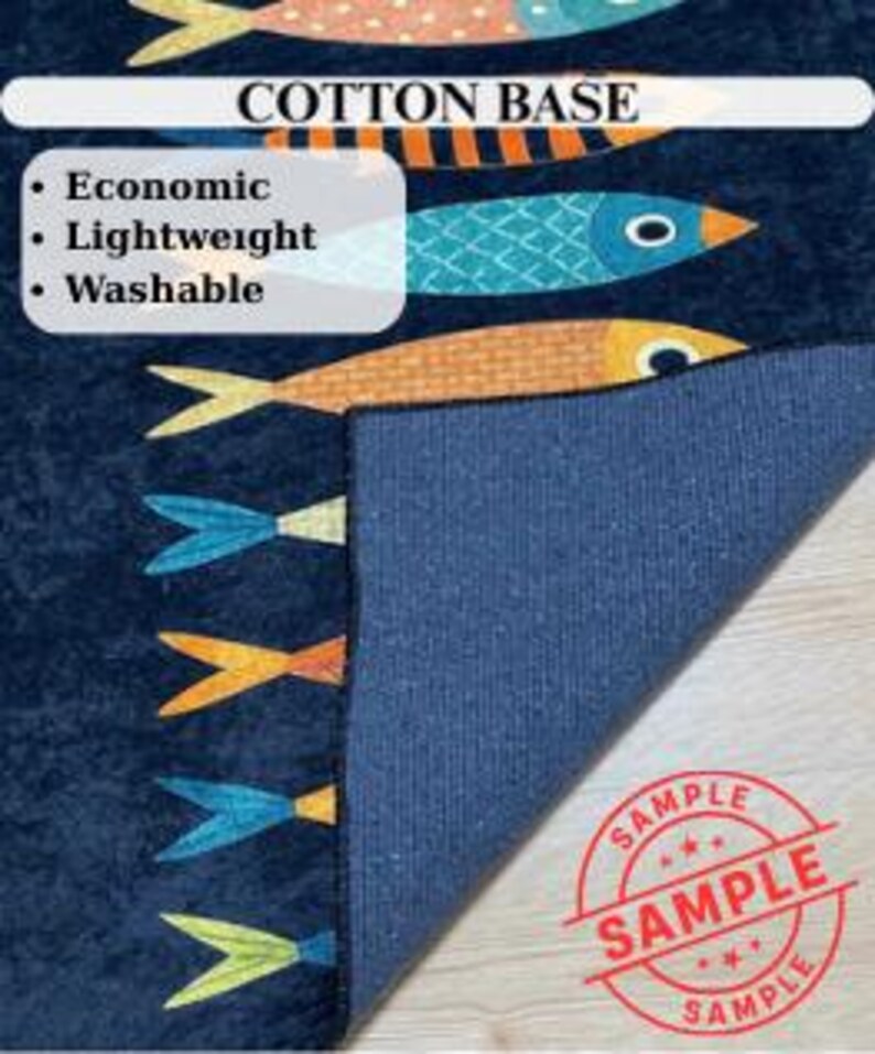 May include: A navy blue cotton base rug with a fish pattern in orange, teal, and yellow. The rug has a rolled-up corner, revealing the blue backing. Text on the rug reads "COTTON BASE" and "Economic, Lightweight, Washable."