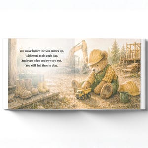 May include: A children's book illustration featuring a teddy bear wearing a construction worker's outfit and hard hat, playing with a toy dump truck. The text on the page reads: "You wake before the sun comes up... You still find time to play."