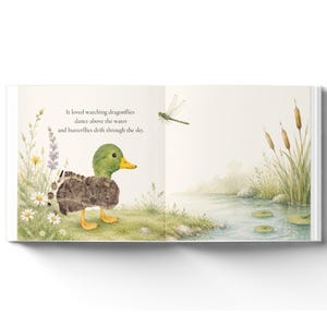 May include: An open children's book page featuring a watercolor illustration of a green-headed duckling standing near a pond with cattails, daisies, and a dragonfly. The text reads: It loved watching dragonflies dance above the water and butterflies drift through the sky.