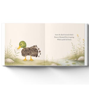 May include: An open children's book page featuring a watercolor illustration of a duck with a textured brown body and green head, standing near a small stream. The text reads: Soon the duck learned which flowers bloomed first in spring. Which paths led home.