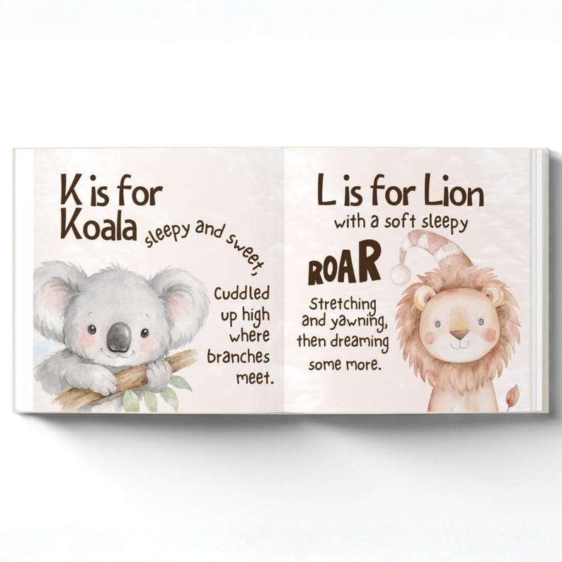 May include: An open book with animal illustrations. One page shows a koala with the text "K is for Koala." The opposite page features a lion wearing a nightcap, with the text "L is for Lion." The illustrations are in a soft, watercolour style.