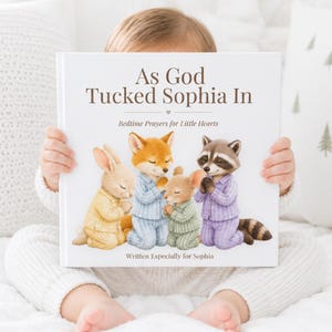 May include: A hardcover book titled As God Tucked Sophia In, Bedtime Prayers for Little Hearts. The white cover features an illustration of a rabbit, fox, mouse, and raccoon in striped pajamas kneeling with hands together in prayer.