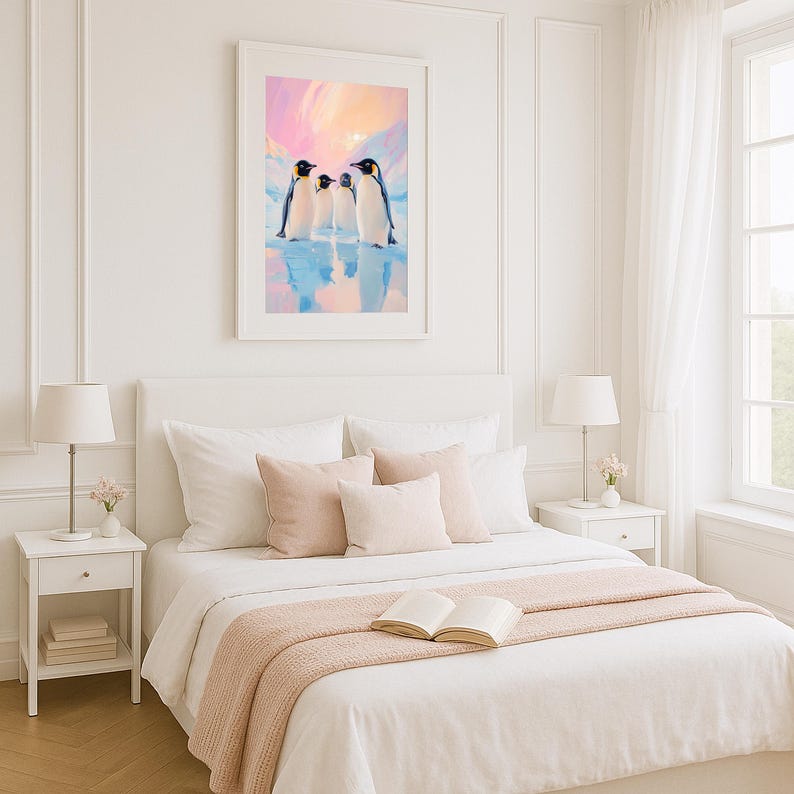 May include: A framed art print featuring three penguins standing on ice, set against a pastel sky. The artwork is displayed above a bed with white linens, blush pillows, and a matching throw blanket. A bedside table with a lamp is visible.