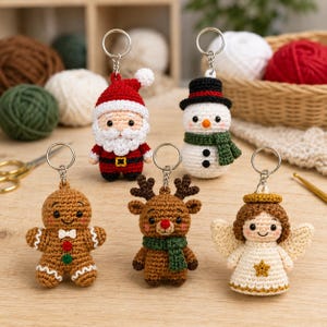 Op de afbeelding: Een set van vijf gehaakte kerst-sleutelhangers met een kerstman in een rood pak, een sneeuwpop met een zwarte hoge hoed en groene sjaal, een peperkoekmannetje, een rendier met een gewei en een engel met gouden vleugels.