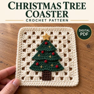 Puede incluir: Un posavasos cuadrado de ganchillo con una base de granny square de color crema y una aplicación de árbol de Navidad verde oscuro en el centro. El árbol está decorado con pequeñas esferas rojas y detalles de punto de cruz amarillo, con una estrella.