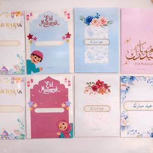 Könnte beinhalten: Eine Sammlung von Eid Mubarak-Grußkarten mit verschiedenen Designs. Einige Karten zeigen Cartoon-Figuren, Blumenarrangements und arabische Kalligraphie. Die Karten sind in Blau-, Rosa- und Weißtönen mit goldenen Akzenten gehalten.